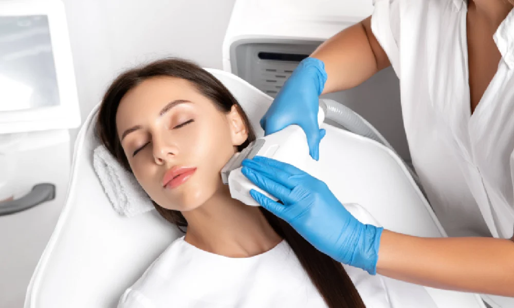 Young woman receiving an IPL photofacials in Destin, FL, lying relaxed with eyes closed while a professional in blue gloves treats her face with a handheld device